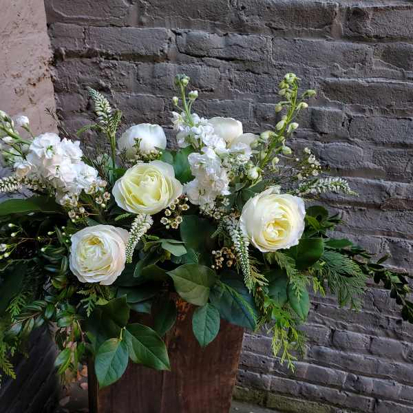 White roses and white blooms in a rustic wooden container