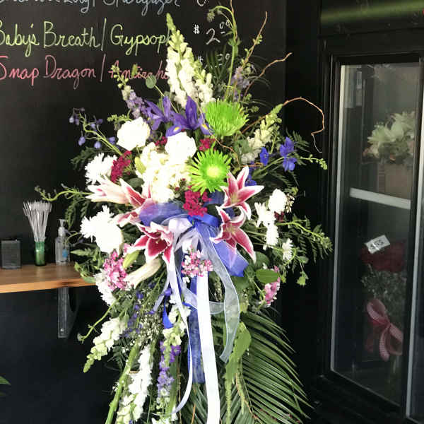 Tall standing floral spray with lilies, snapdragons, and ribbon