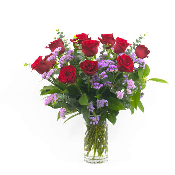 Red roses and purple filler flowers in a clear glass vase