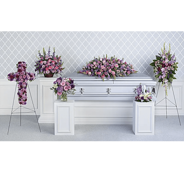 Pink and purple funeral flowers arranged around a silver casket