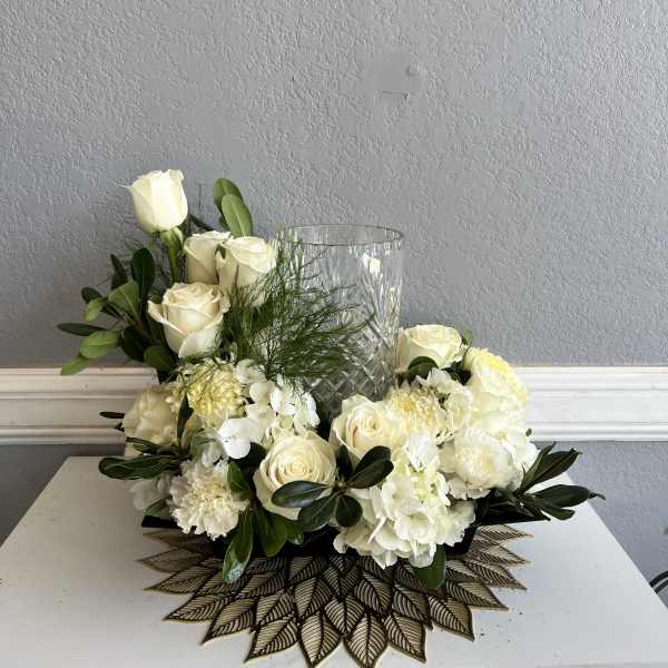 White roses and hydrangeas arranged around a clear glass vase