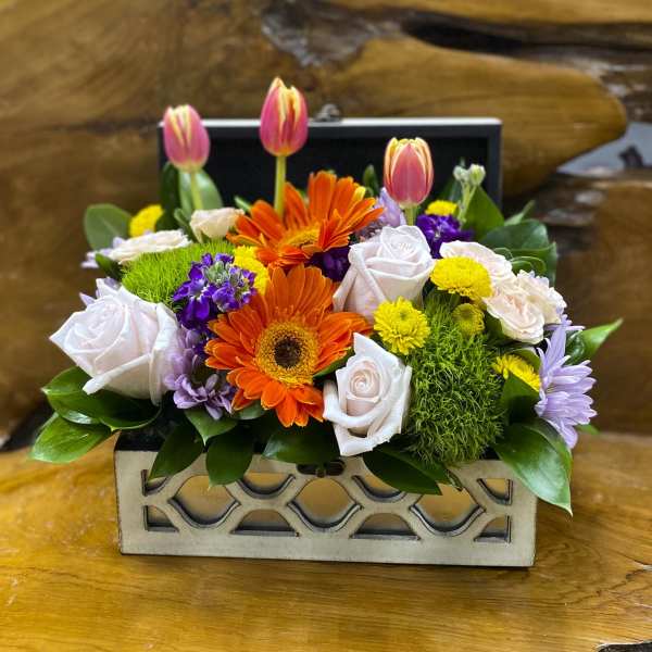 Mixed flower arrangement in a decorative rectangular box with pink tulips and orange gerberas