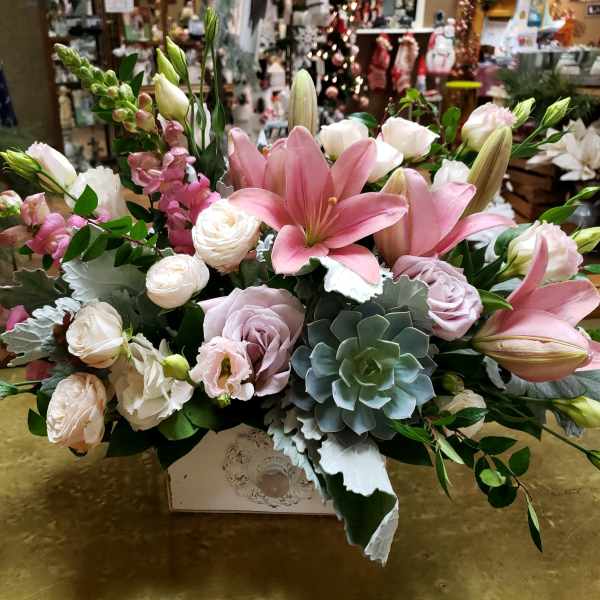 Pink lilies and pale roses arranged in a decorative box
