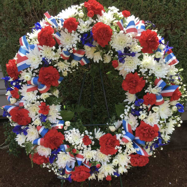 Large patriotic floral wreath with red, white, and blue flowers on a stand