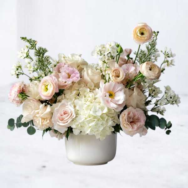 Blush and cream floral arrangement in a white vase