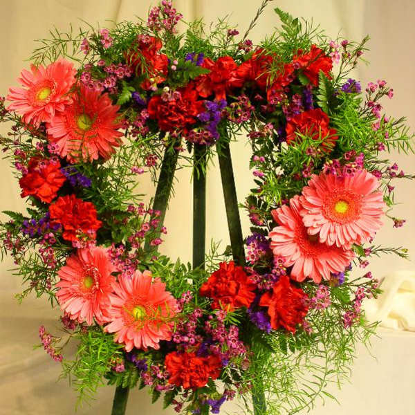 Heart-shaped floral wreath with pink gerbera daisies and red carnations