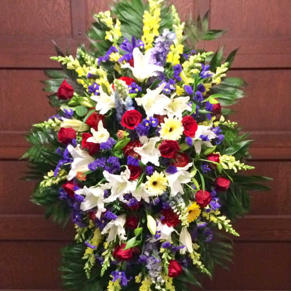 Standing funeral spray with red, white, yellow, and purple flowers