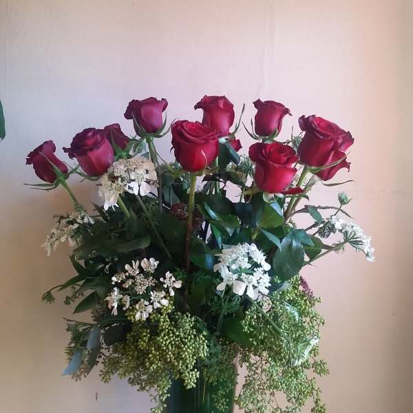 Tall vase arrangement of red roses and white filler flowers