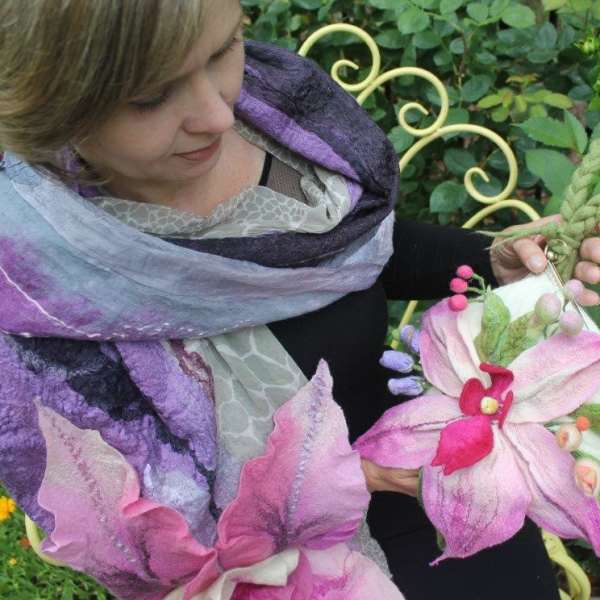 Woman holding two pink and purple floral accessories outdoors