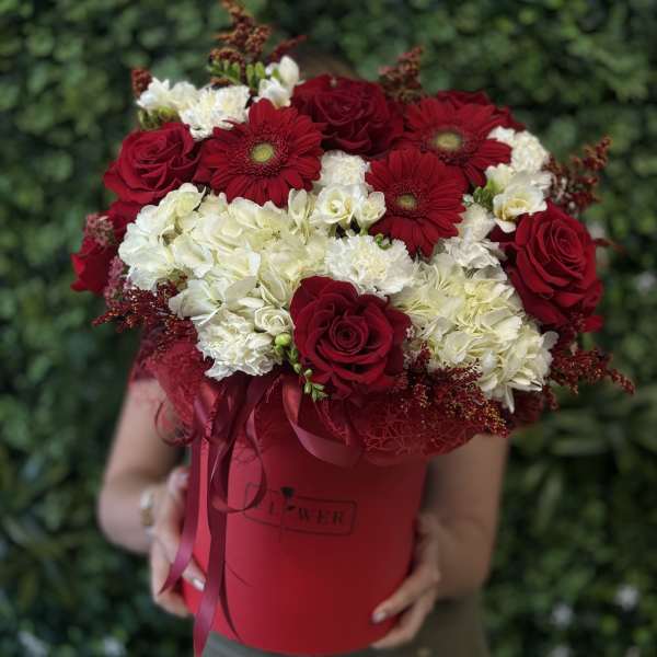 Red roses and white hydrangeas in a red hatbox