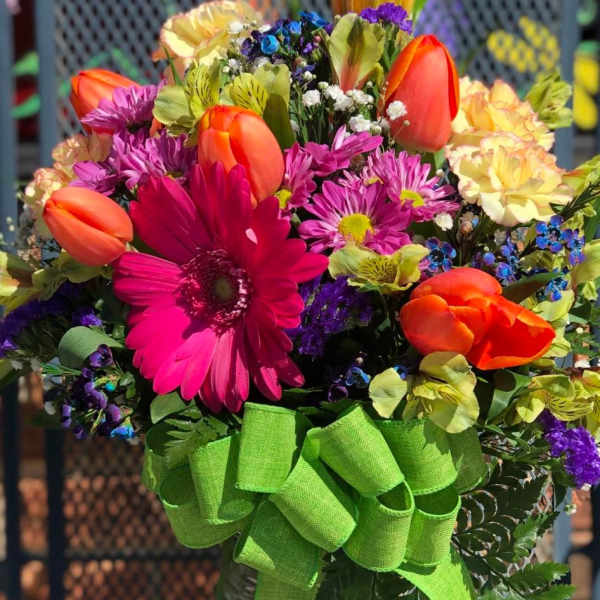 Colorful mixed bouquet in a glass vase with a green ribbon