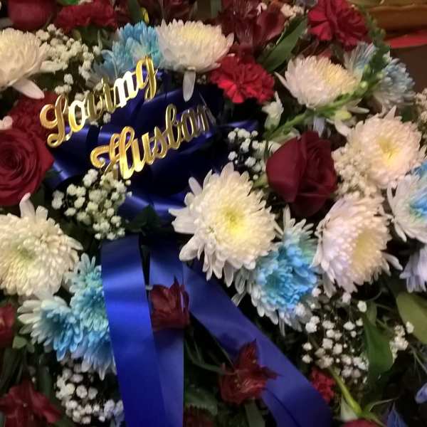 Large floral arrangement with red roses, white chrysanthemums, and blue-dyed blooms