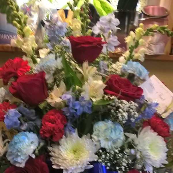 Mixed bouquet with red roses, blue hydrangeas, white lilies, and a blue ribbon