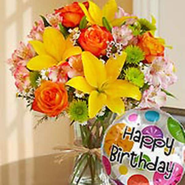 Bright mixed bouquet in a glass vase with a birthday balloon