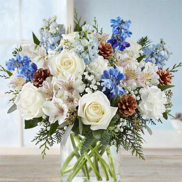 White roses and blue flowers in a clear glass vase