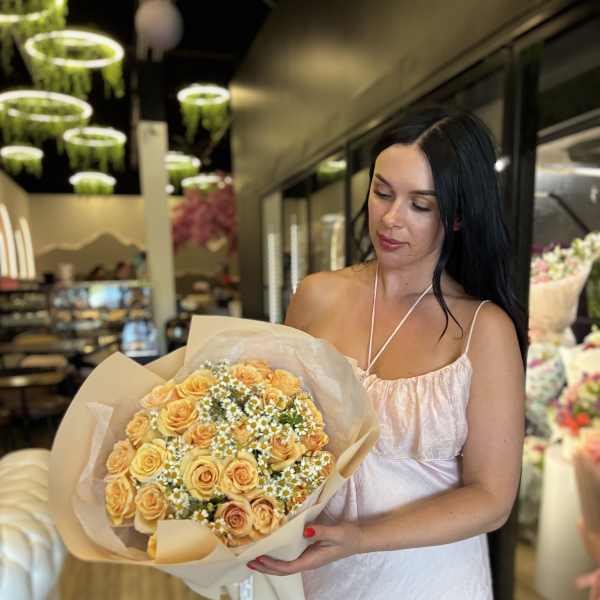 Woman holding a bouquet of peach roses and small white daisies