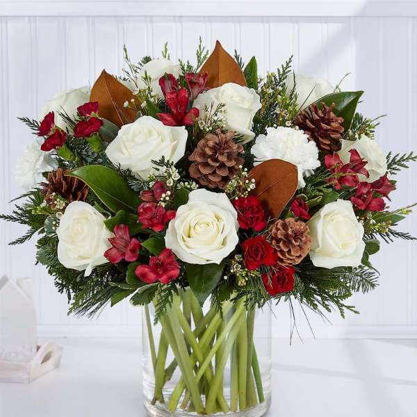 Bouquet of white roses and red flowers in a clear glass vase