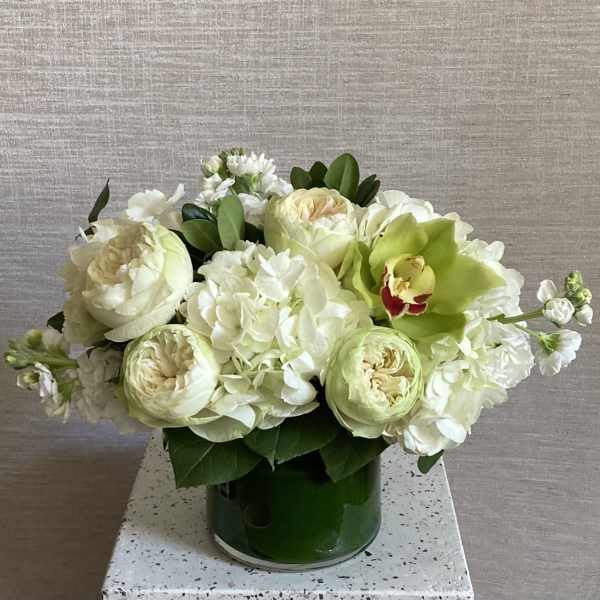 White and pale green floral arrangement in a green vase