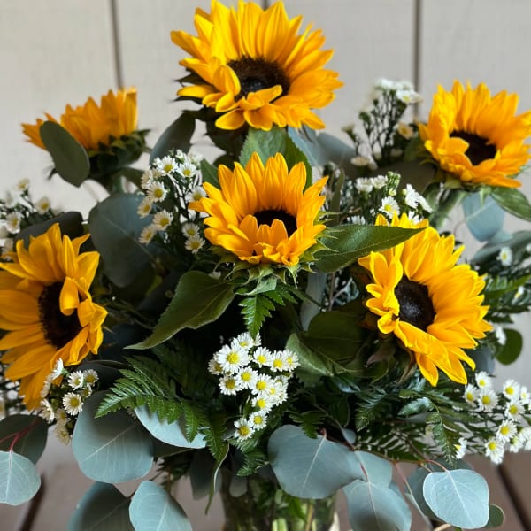 Bouquet of sunflowers and small white daisies in a glass vase