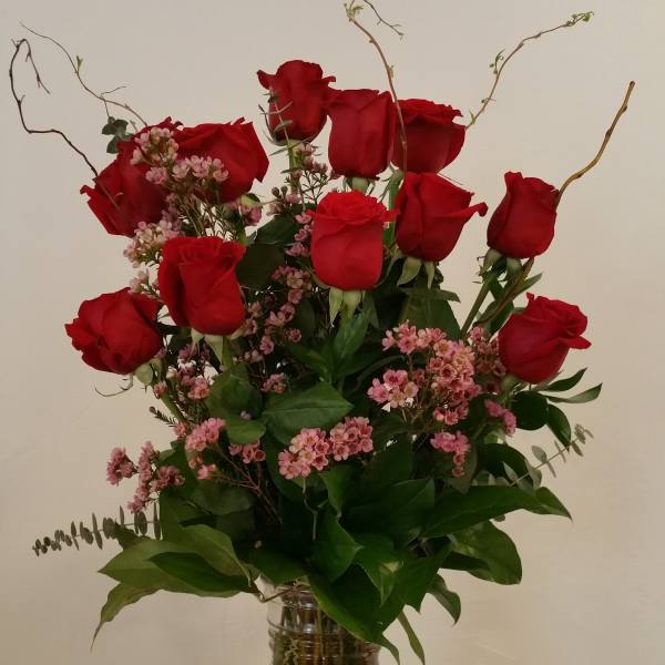 Red roses and pink filler flowers in a clear glass vase