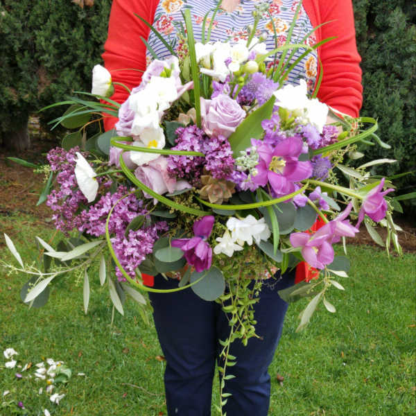 Large bouquet of purple and white flowers held outdoors