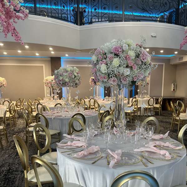 Tall pastel floral centerpieces on banquet tables in a decorated event hall