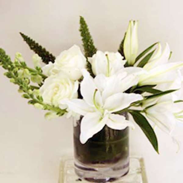 White lilies and roses arranged in a clear glass vase