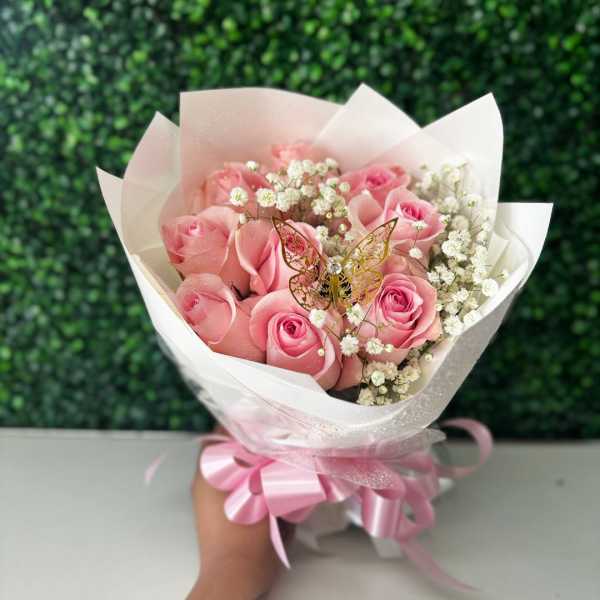 Pink rose bouquet wrapped in white paper with a ribbon