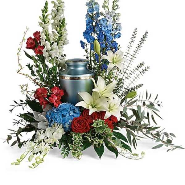 Floral funeral arrangement around a blue urn with red, white, and blue flowers