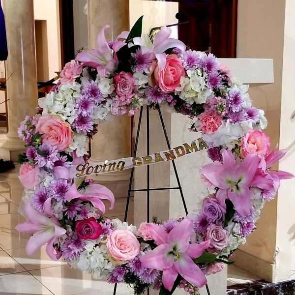 Pink and white floral wreath on an easel with a "Loving GRANDMA" ribbon