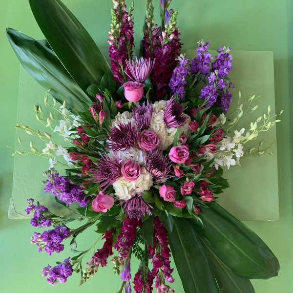 Large pink and purple floral arrangement with broad green leaves