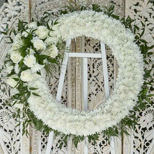 White floral funeral wreath with roses and chrysanthemums on a stand