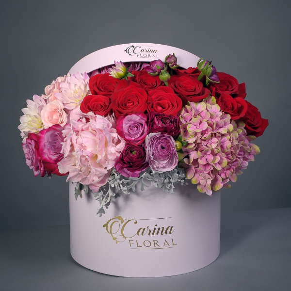 Round box arrangement of red, pink, and purple flowers