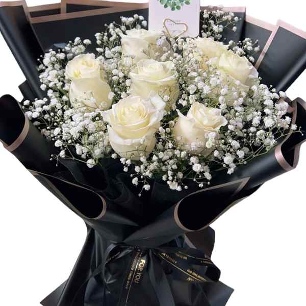 Bouquet of white roses and baby's breath wrapped in black paper