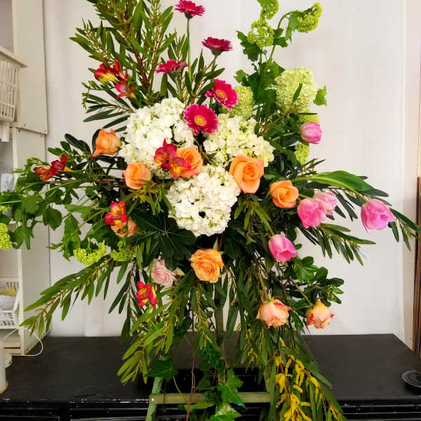 Large standing floral spray with pink, orange, white, and green blooms