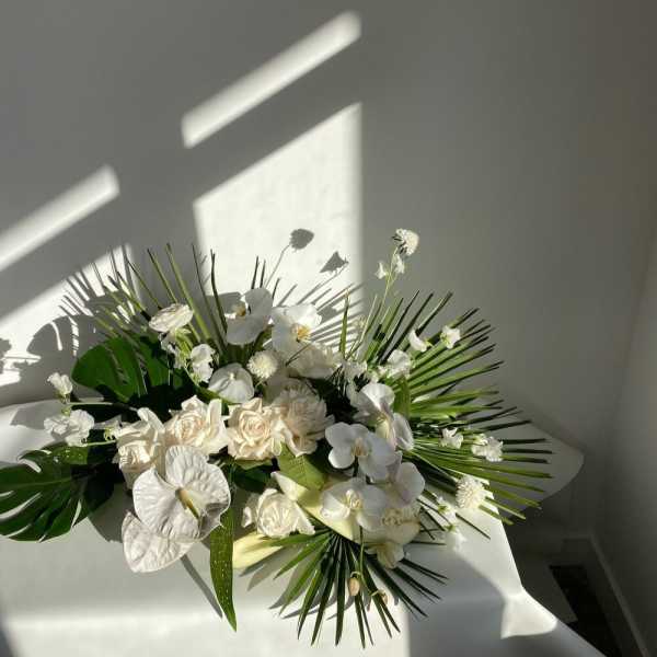 White floral arrangement with orchids and roses on a table