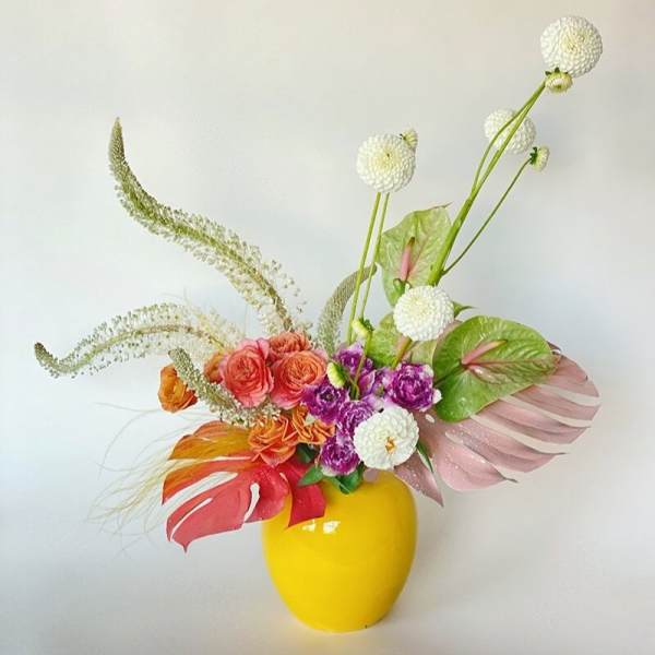 Colorful floral arrangement in a yellow vase with white pom-pom blooms