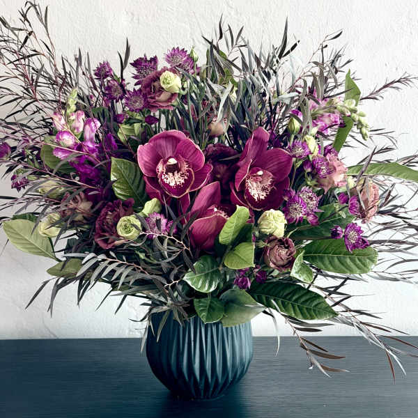 Purple orchid and rose arrangement in a blue vase