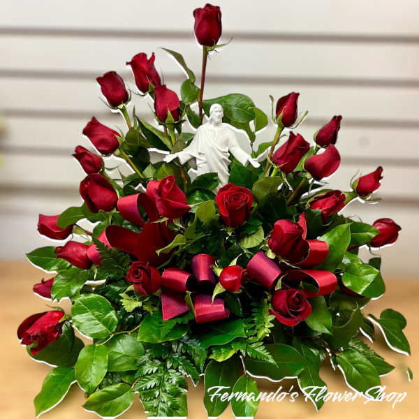 Fan-shaped arrangement of red roses with a white Jesus figurine and red ribbon loops