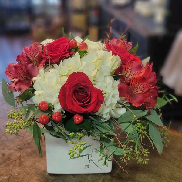 Red roses and white hydrangeas in a white square vase