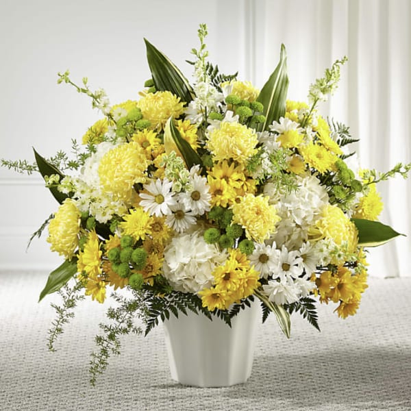 Yellow and white mixed flower arrangement in a white vase