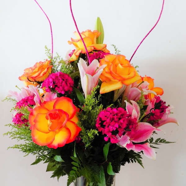 Bright orange and pink roses in a clear glass vase.