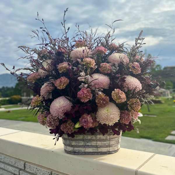 Pink and cream pompon flowers in a woven basket arrangement