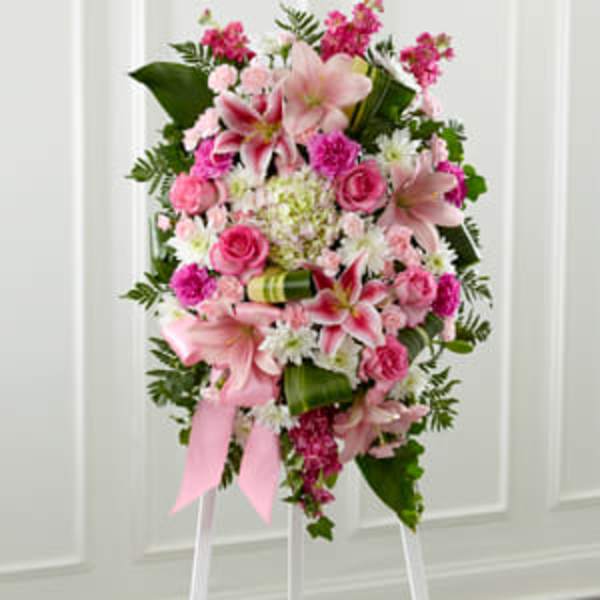 Standing pink and white floral spray with lilies and roses on a white easel