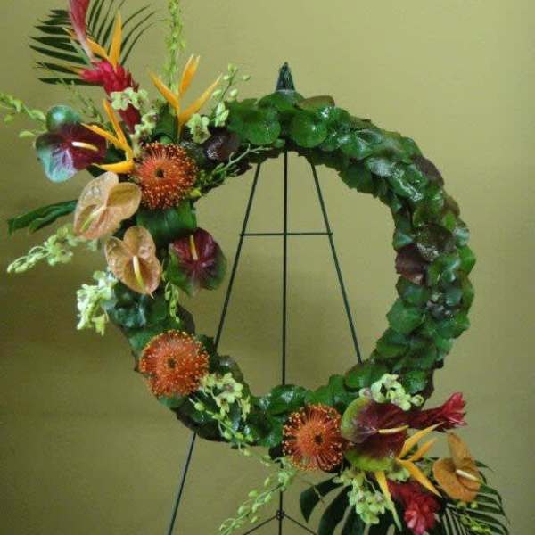 Tropical floral wreath with orange and red blooms on a black stand