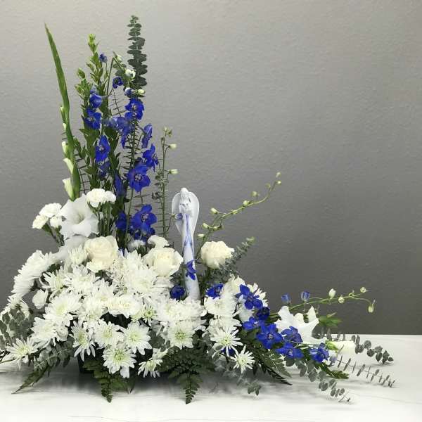 White and blue floral arrangement with tall spikes in a low container