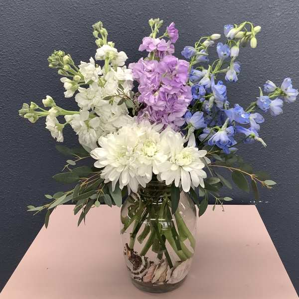 Bouquet of white, pink, and blue flowers in a glass vase