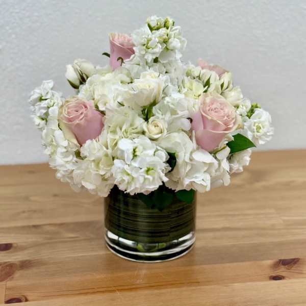 Pink roses and white flowers arranged in a glass vase