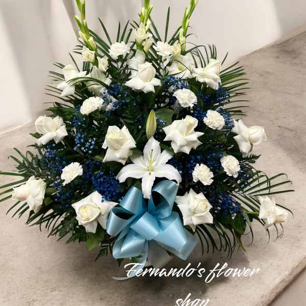 Fan-shaped white roses, carnations, and lilies with blue accents and a light blue bow.