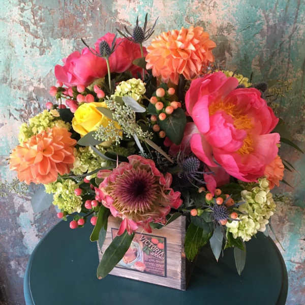 Colorful bouquet with pink and orange blooms in a wooden box